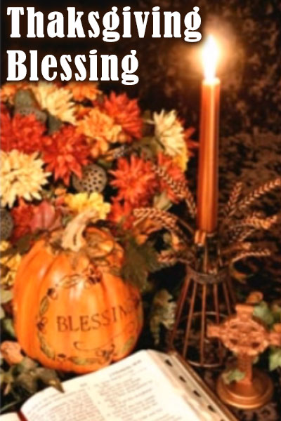 A candle lights a bouquet made of autumn-colored flowers, a book, and a pumpkin with the word blessing carved into it.