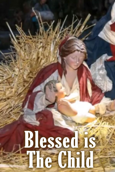 A Mary sculpture from a Nativity scene. Baby Jesus is cradled in her lap. Blessed is the Child is written below them.