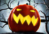 A jack o' lantern with glowing eyes. There is fog, and a skeletal tree in the background.