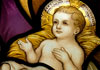 An illustration of baby Jesus in his manger, with a glowing halo of light around his head.