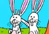 Two bunnies pose for a photo. One bunny is holding two fingers up behind the other bunny’s head, to create a comical bunny ears effect for the photo.