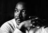 Martin Luther King Jr. looks contemplatively into the distance, and rests his cheek on his hands.