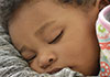 A black child sleeping peacefully in someone's arms.