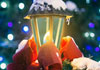 A softly lit street lamp, with snow on top, and a big red bow around the bottom. There are softly blurred blue and silver Christmas lights in the background. Wishing You Christmas Delight is written at the top.