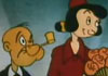 A cartoon still of an old Popeye and Olive Oil cartoon. The couple are nicely dressed and standing side by side, as in a wedding ceremony, which, in fact, it is. Popeye is in a suit with no sailor hat. Above in big white letters it says, 